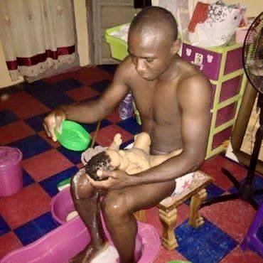 A husband bathing his new-born baby